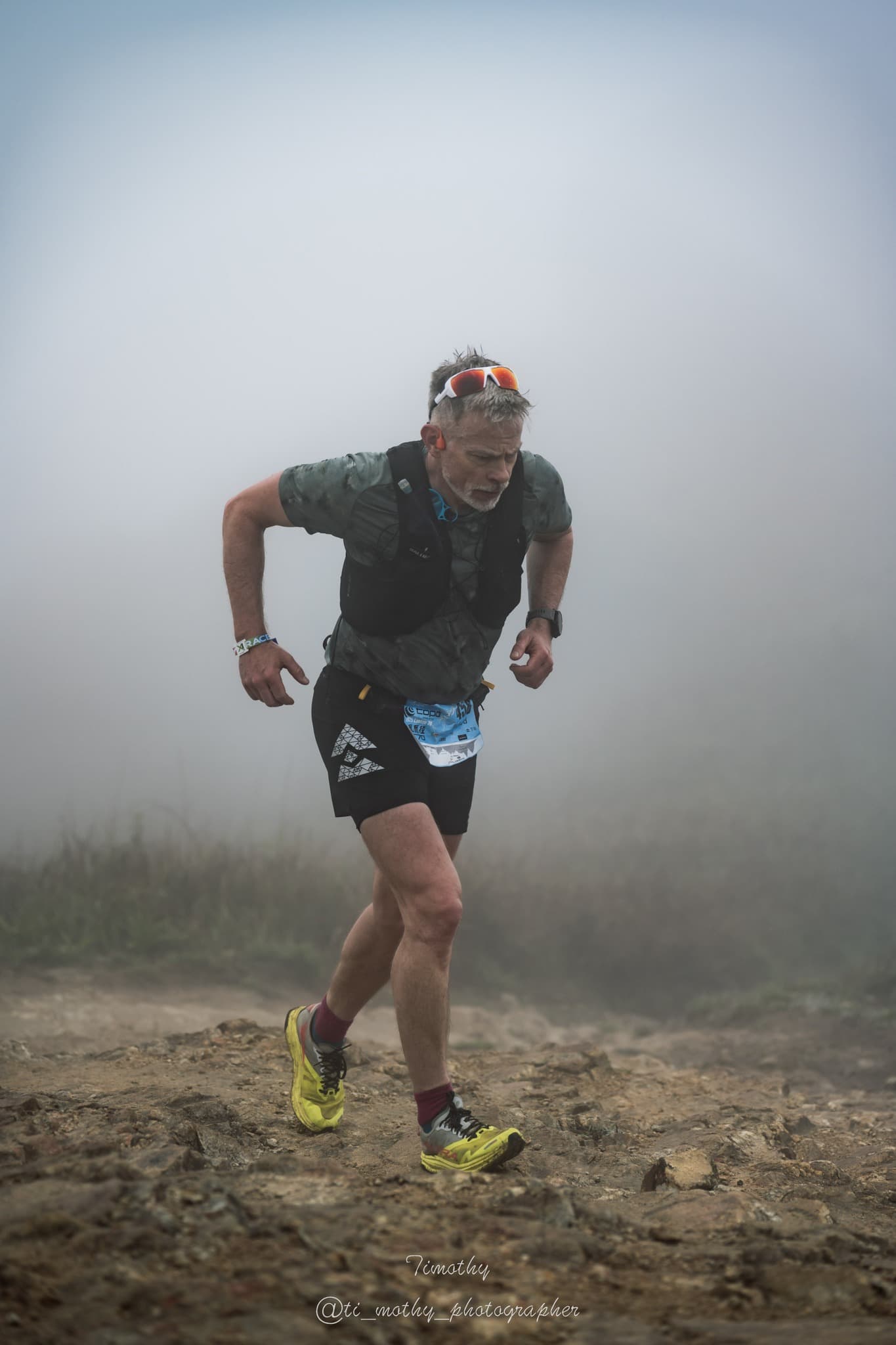 Rich Cowler running alone through dense fog on a dramatic rocky mountain trail